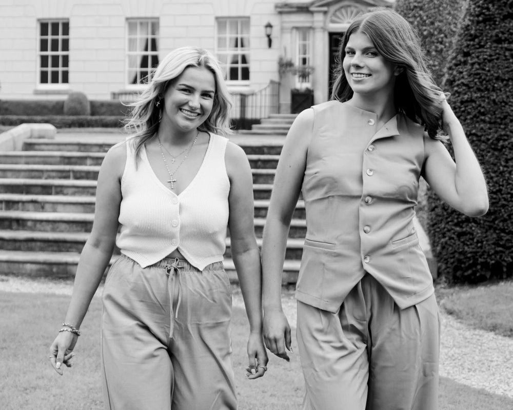 People in matching beige outfits walking and posing along a white building exterior.