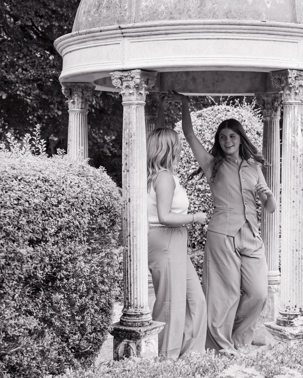 Black and white photo of people posing playfully in a columned gazebo setting.