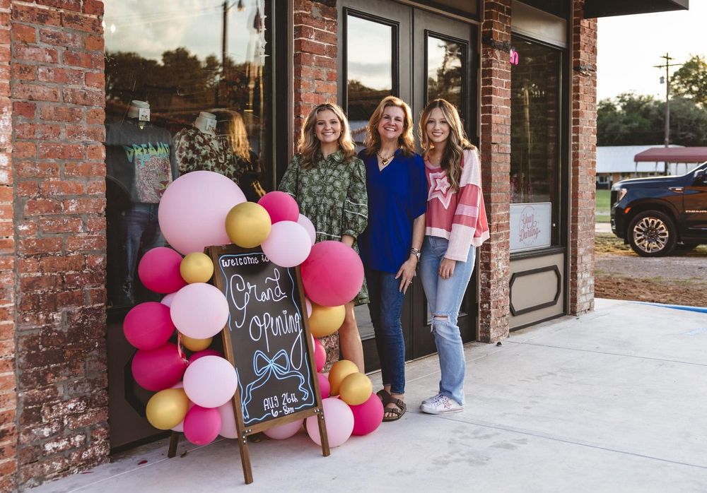 Storefront decorated with colorful balloon arch and chalkboard sign.