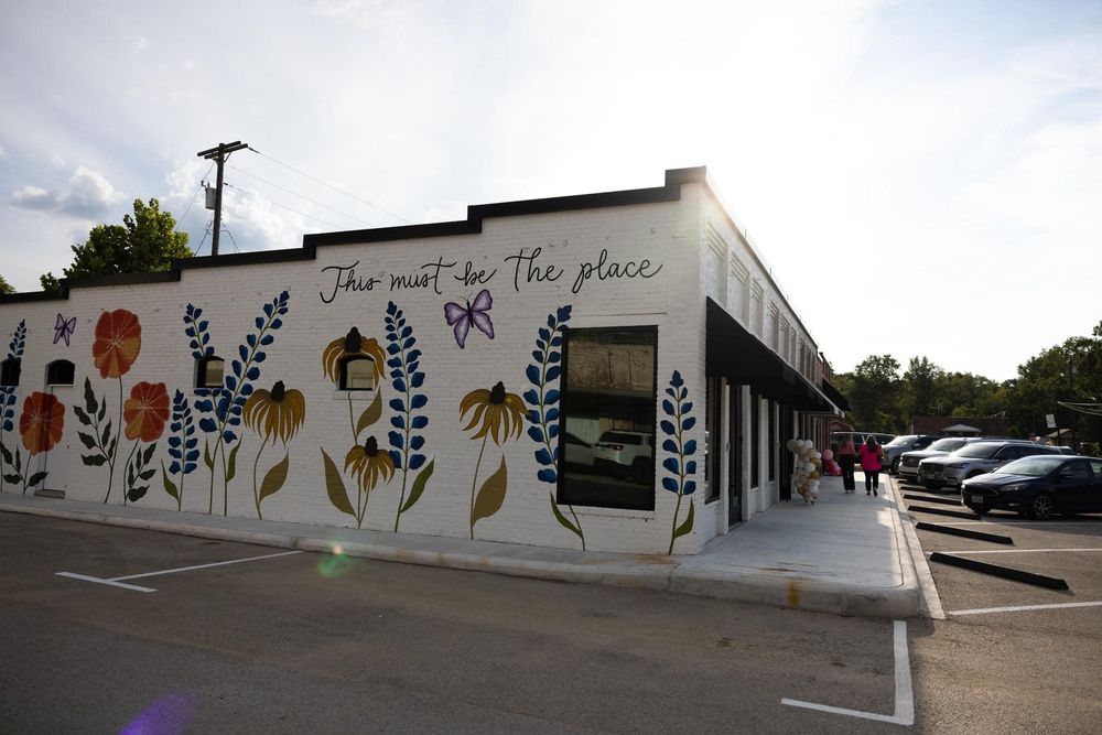 White building exterior with colorful floral mural and text design on wall.