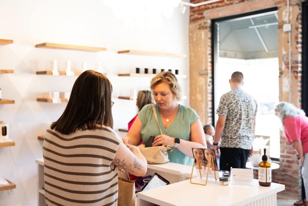 Interior of retail space with wooden shelves and customers seated at counter.