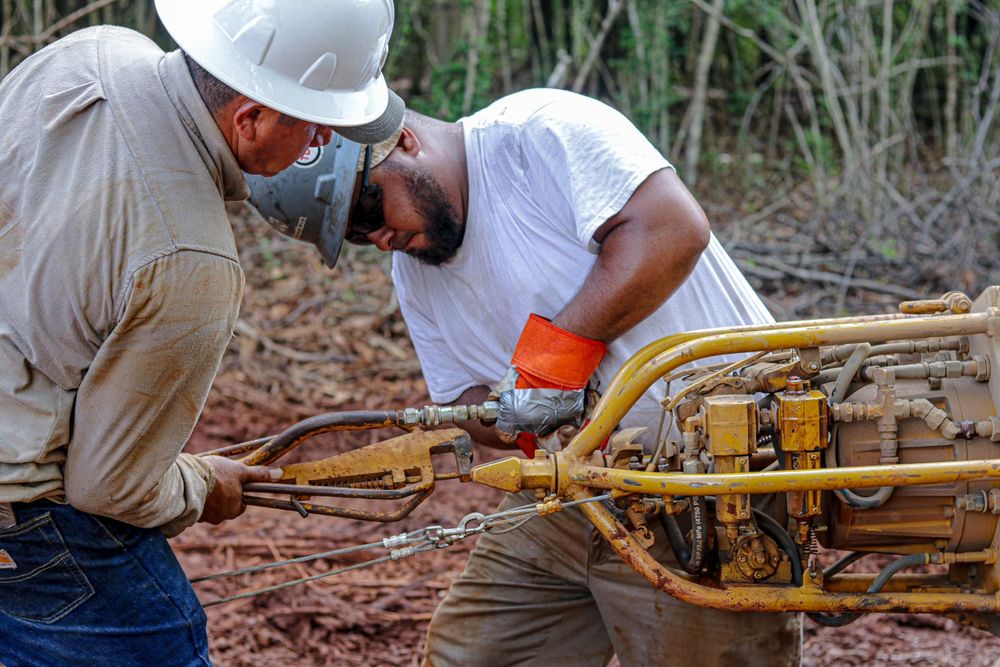 Construction workers examining yellow pipeline equipment in field.