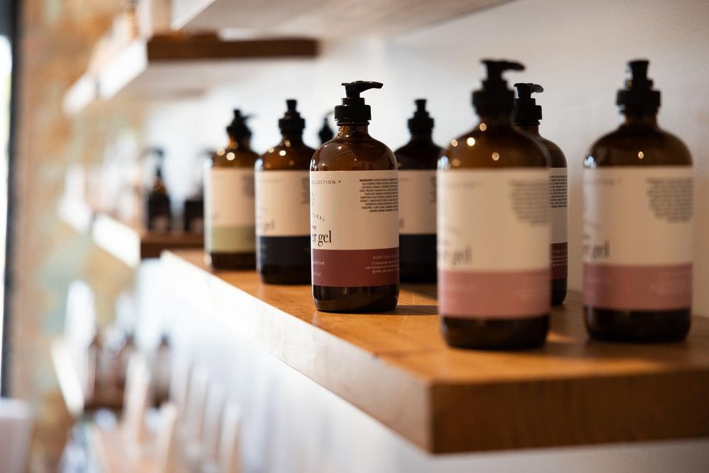 Row of dark amber glass bottles with labels arranged on wooden shelving display.