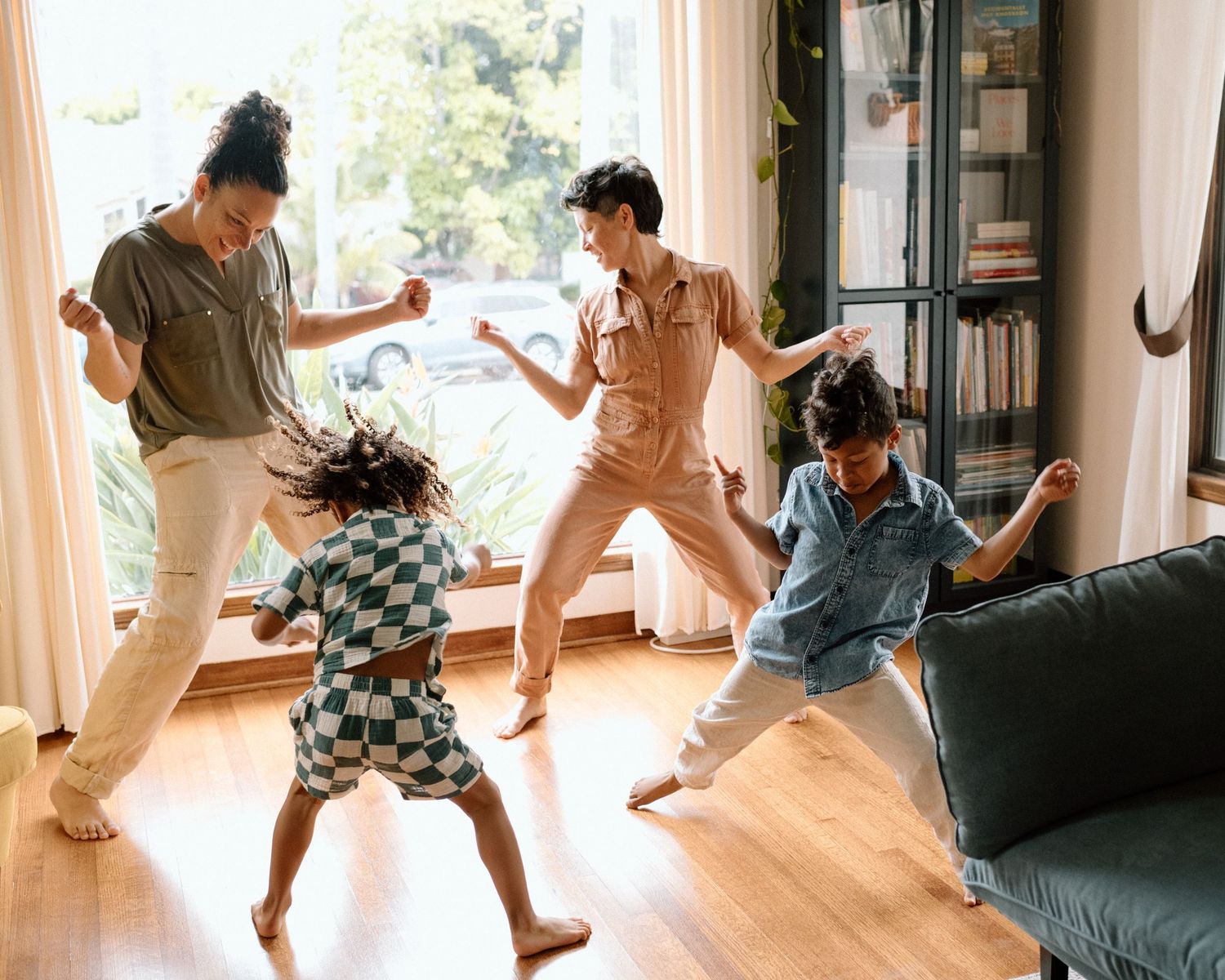 A group of people dancing together in a sunlit living room with a relaxed and joyful energy.