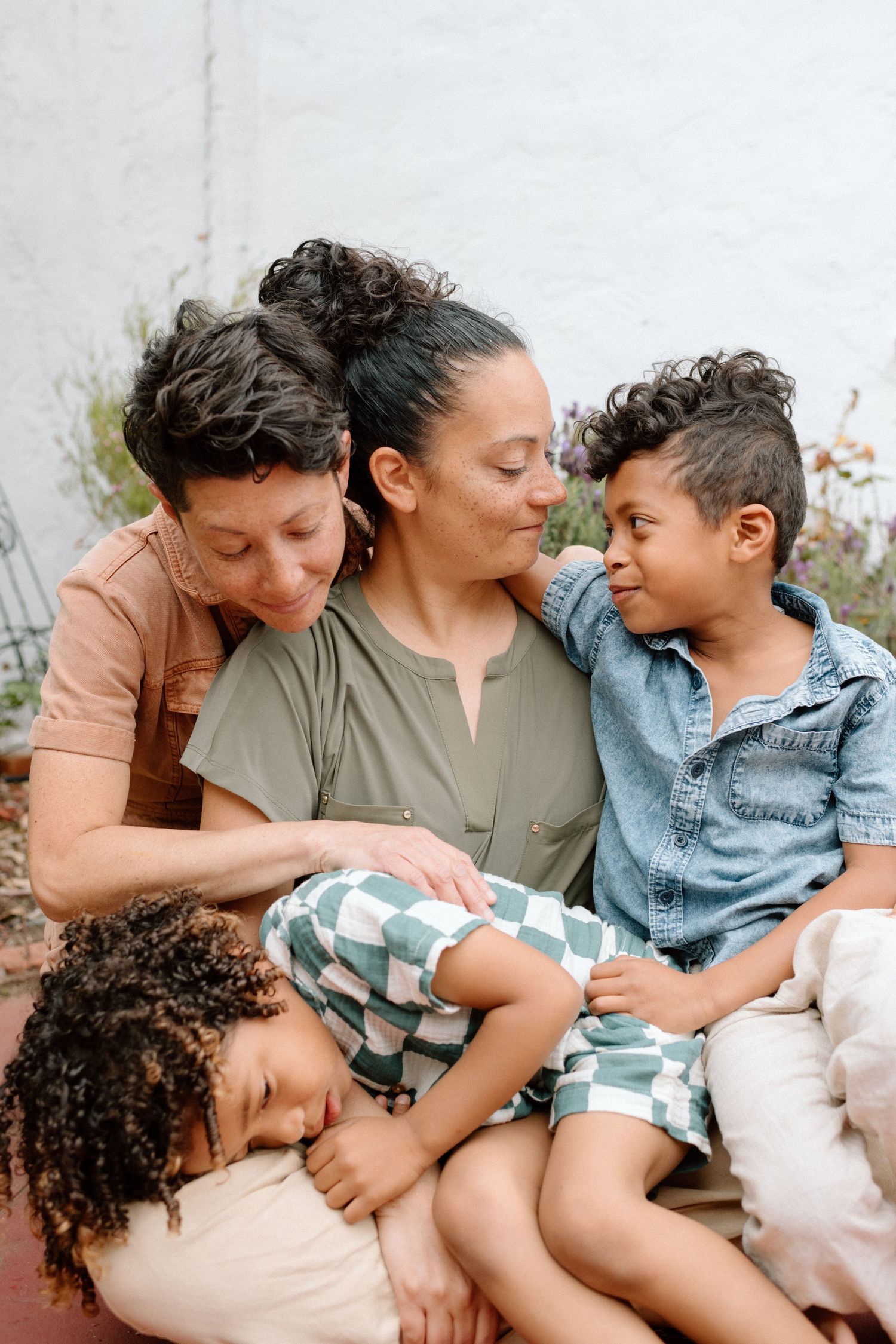 Family sharing tender moment together while cuddling and relaxing outdoors in casual clothing.