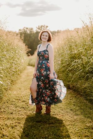 A summer dress with floral print stands out against tall grasses and golden hour sunlight on a country path.