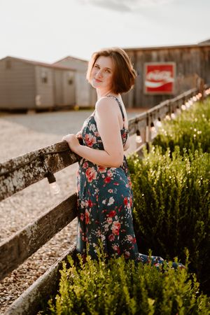A floral dress against lush green bushes in a garden setting during golden hour creates a dreamy summer scene.
