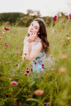 Portrait of someone posing in a dreamy summer wildflower field with pink cosmos flowers in bloom.
