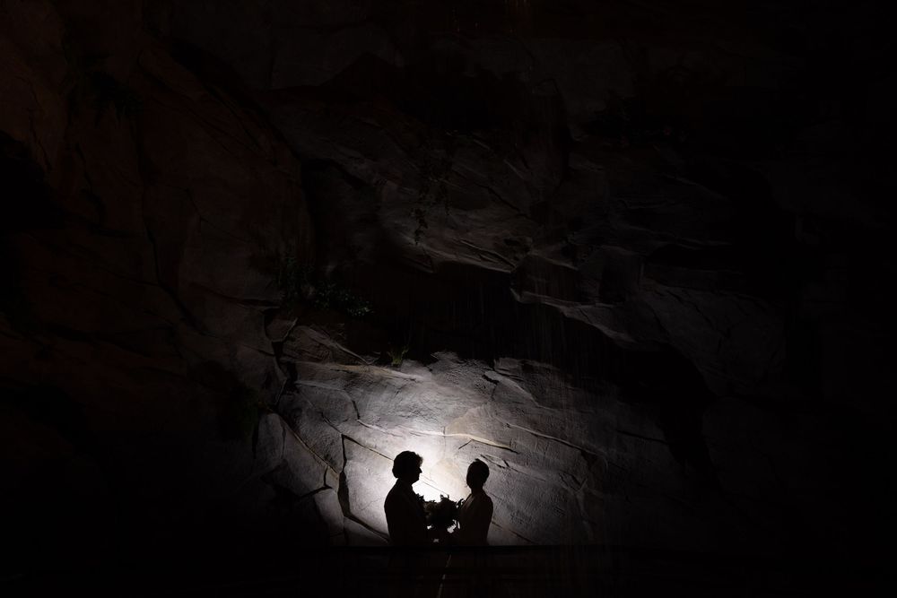 Dramatic silhouette of a couple against a lit cave wall creating a romantic atmosphere.