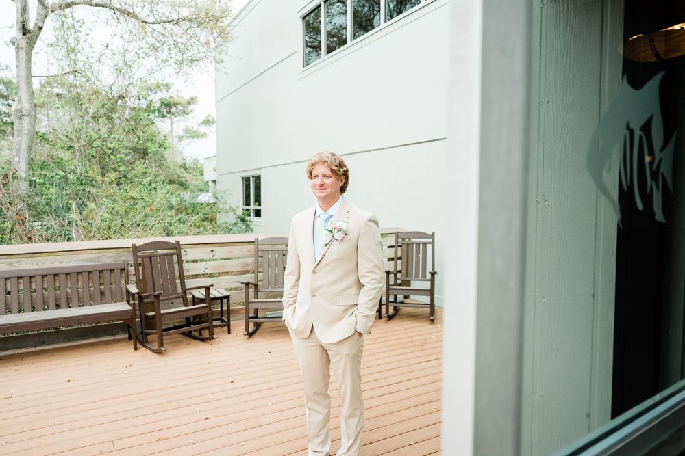 Modern white building exterior with wooden deck and benches for an outdoor wedding venue.