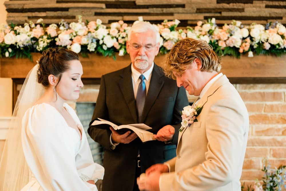 Wedding ceremony with floral arch backdrop during intimate indoor service.