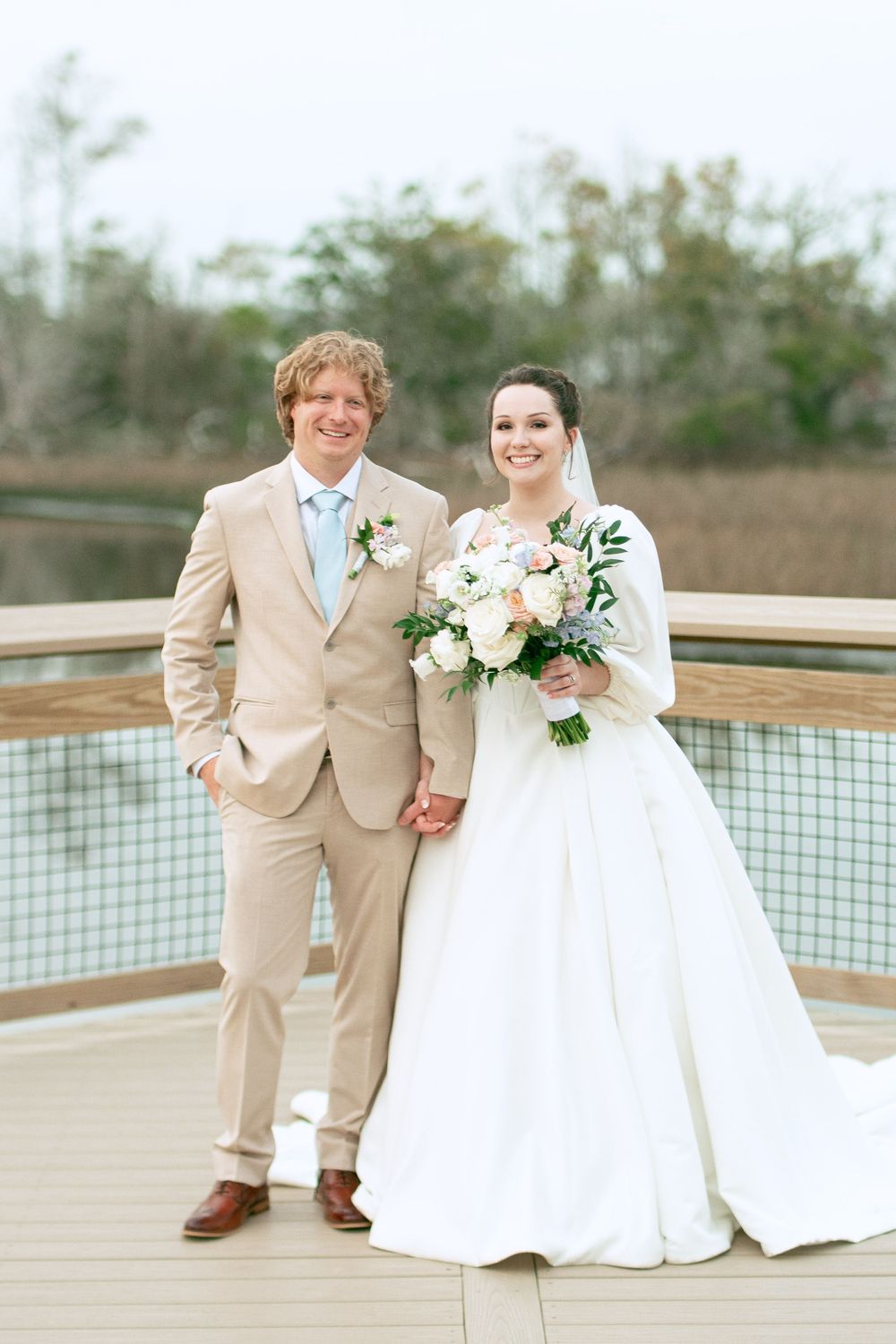 Newlyweds pose together on curved wooden deck during outdoor wedding portraits.