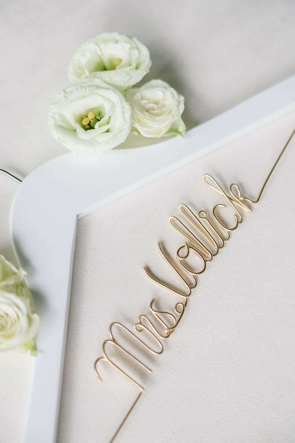 White lisianthus flowers and gold wedding stationery with elegant 'Mrs and Mr' calligraphy text on light background.