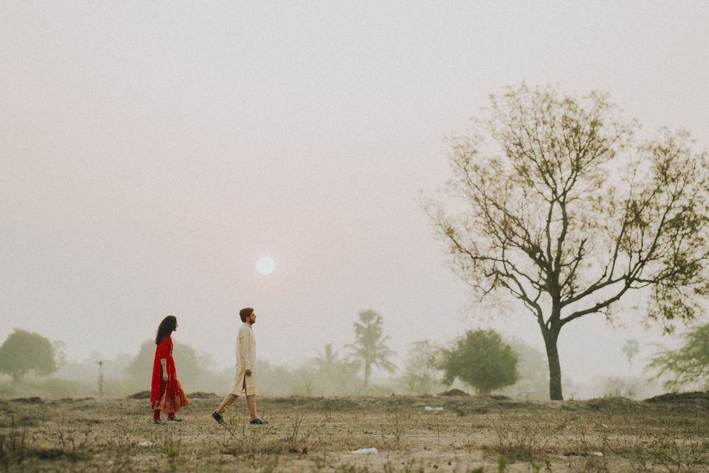 Silhouetted figures walking in misty field at sunset with lone tree in background.