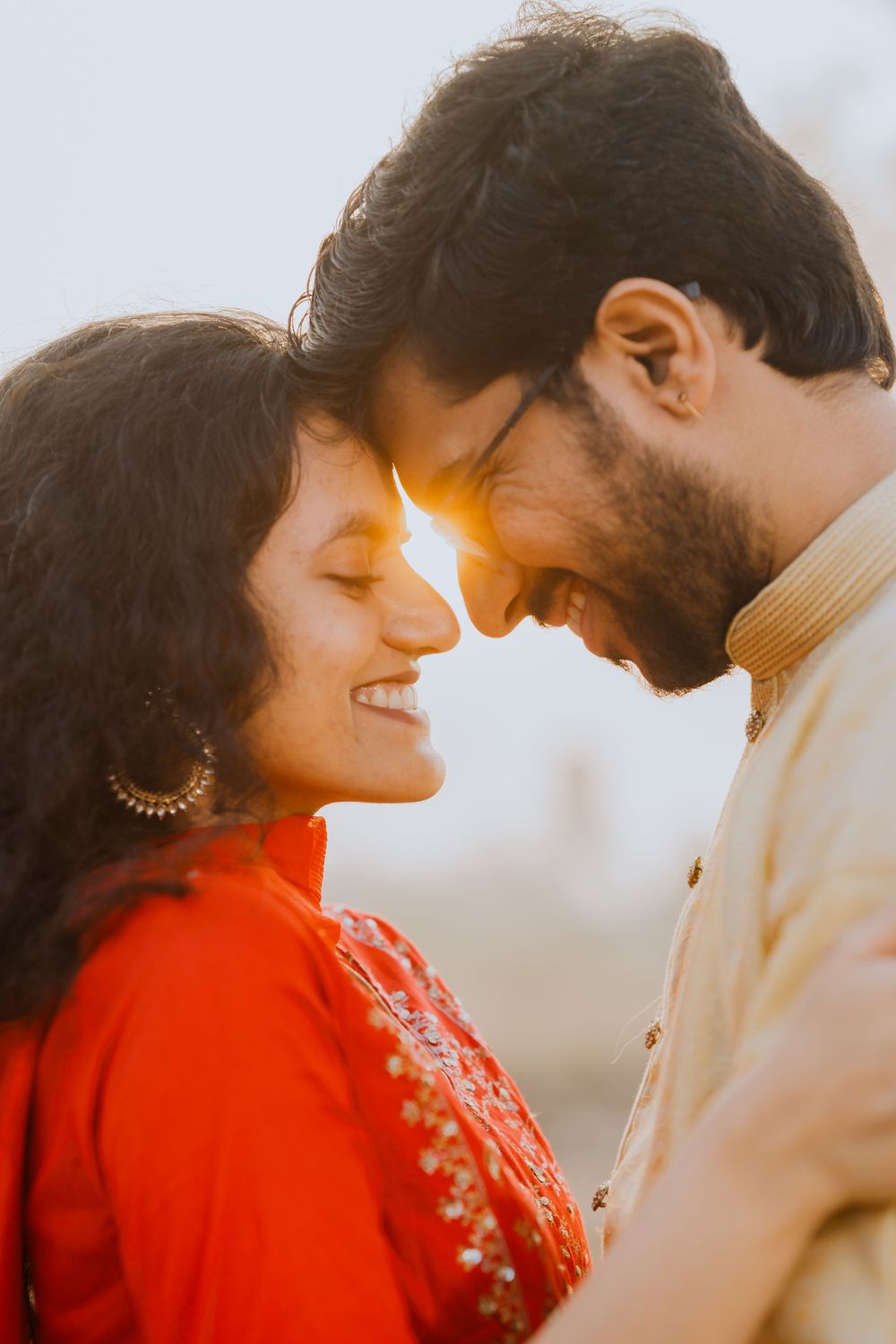 Intimate moment captured at golden hour showing tender affection in traditional Indian attire.