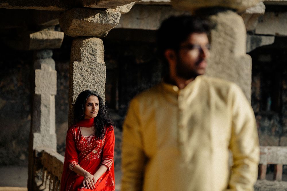 A couple in traditional Indian dress pose at a temple with dramatic lighting.