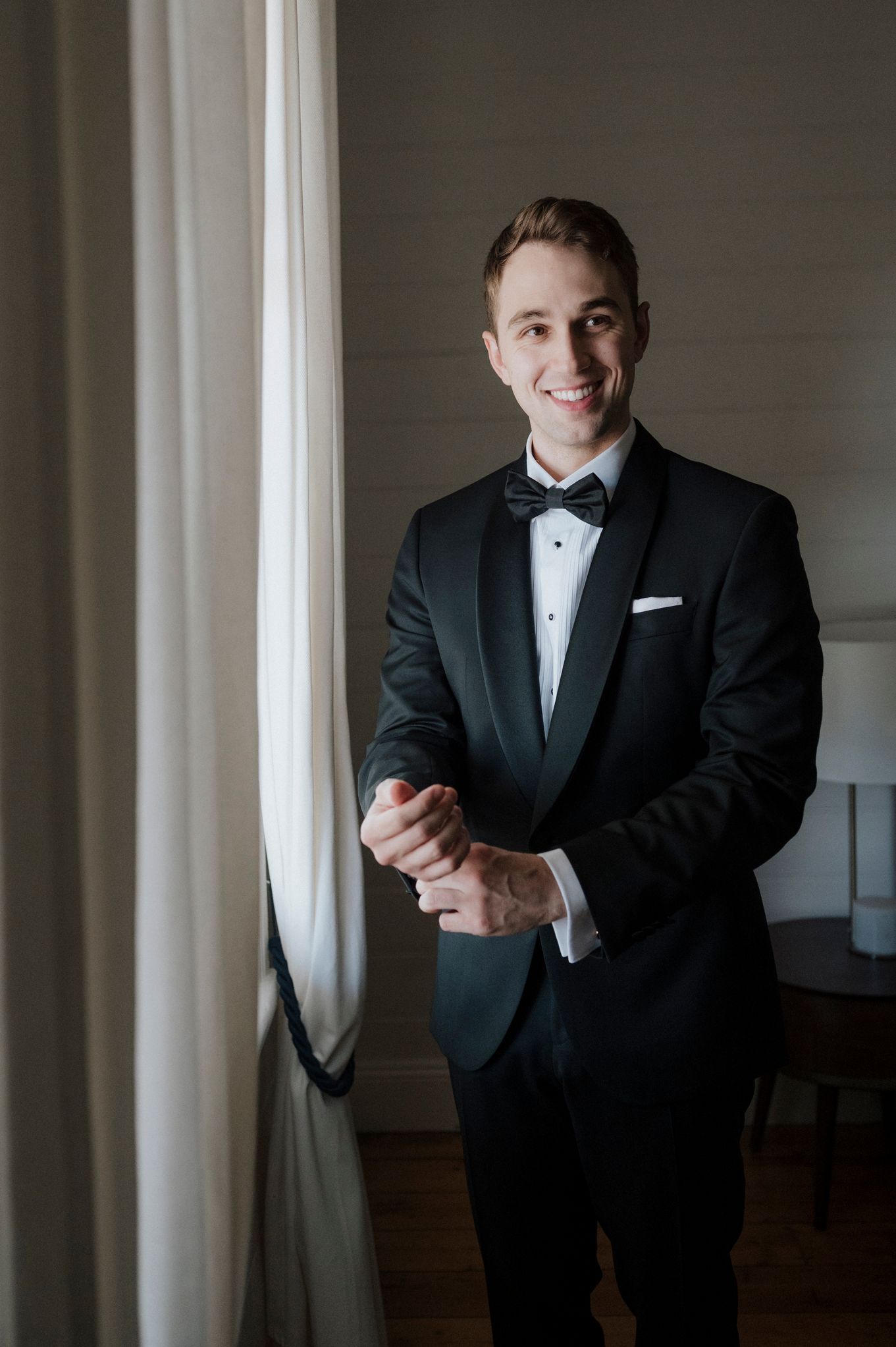 A formal portrait in classic black tuxedo against neutral background.