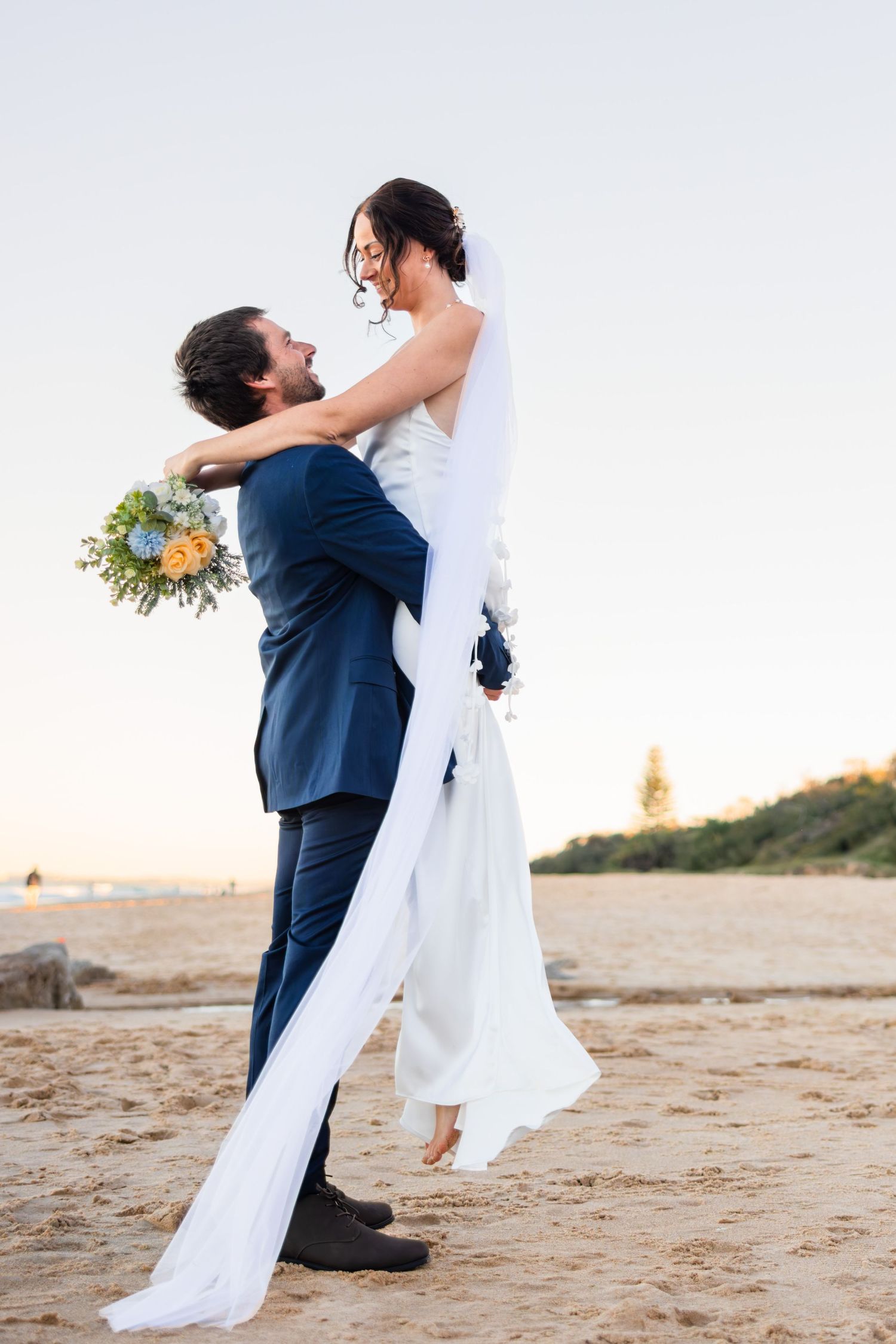 Groom picking up his new bride on the beach after tying the knot.