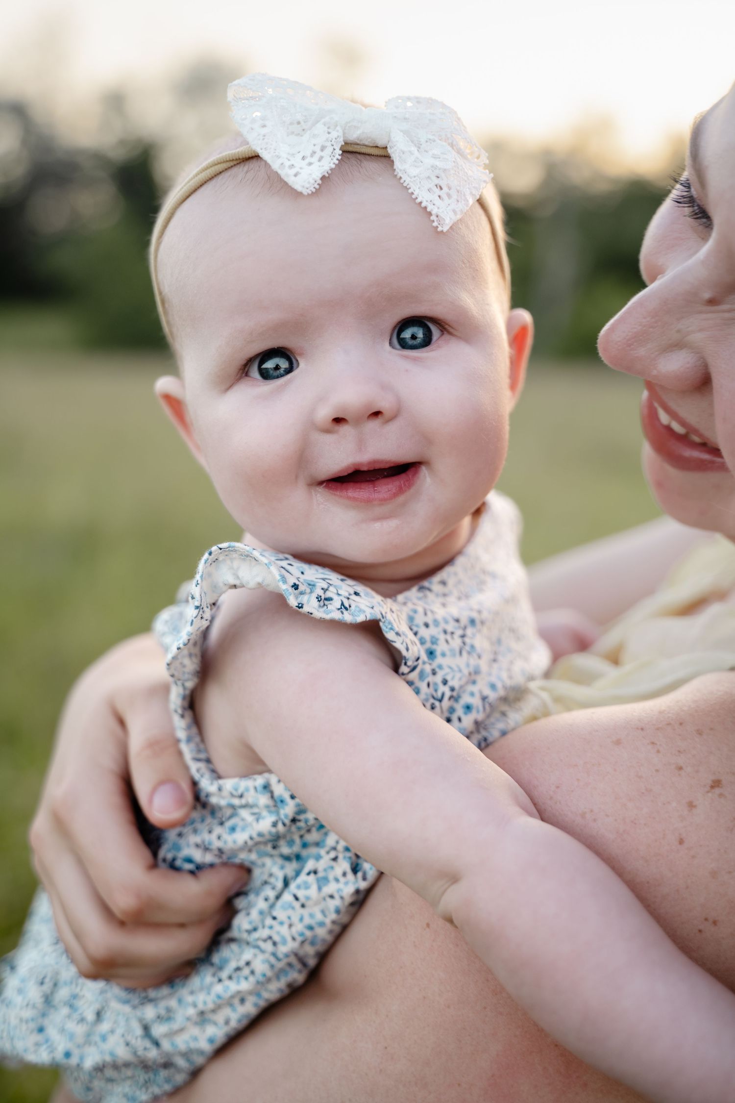 Close-up series of a baby wearing a blue floral outfit and white bow.