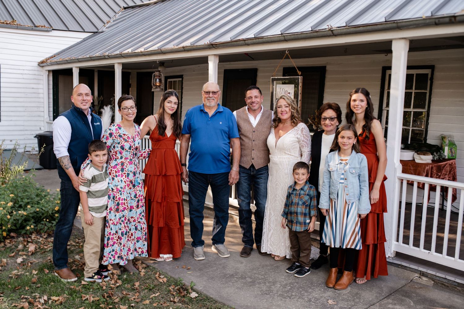 Family gathering on a farmhouse porch with multiple generations in coordinated outfits.