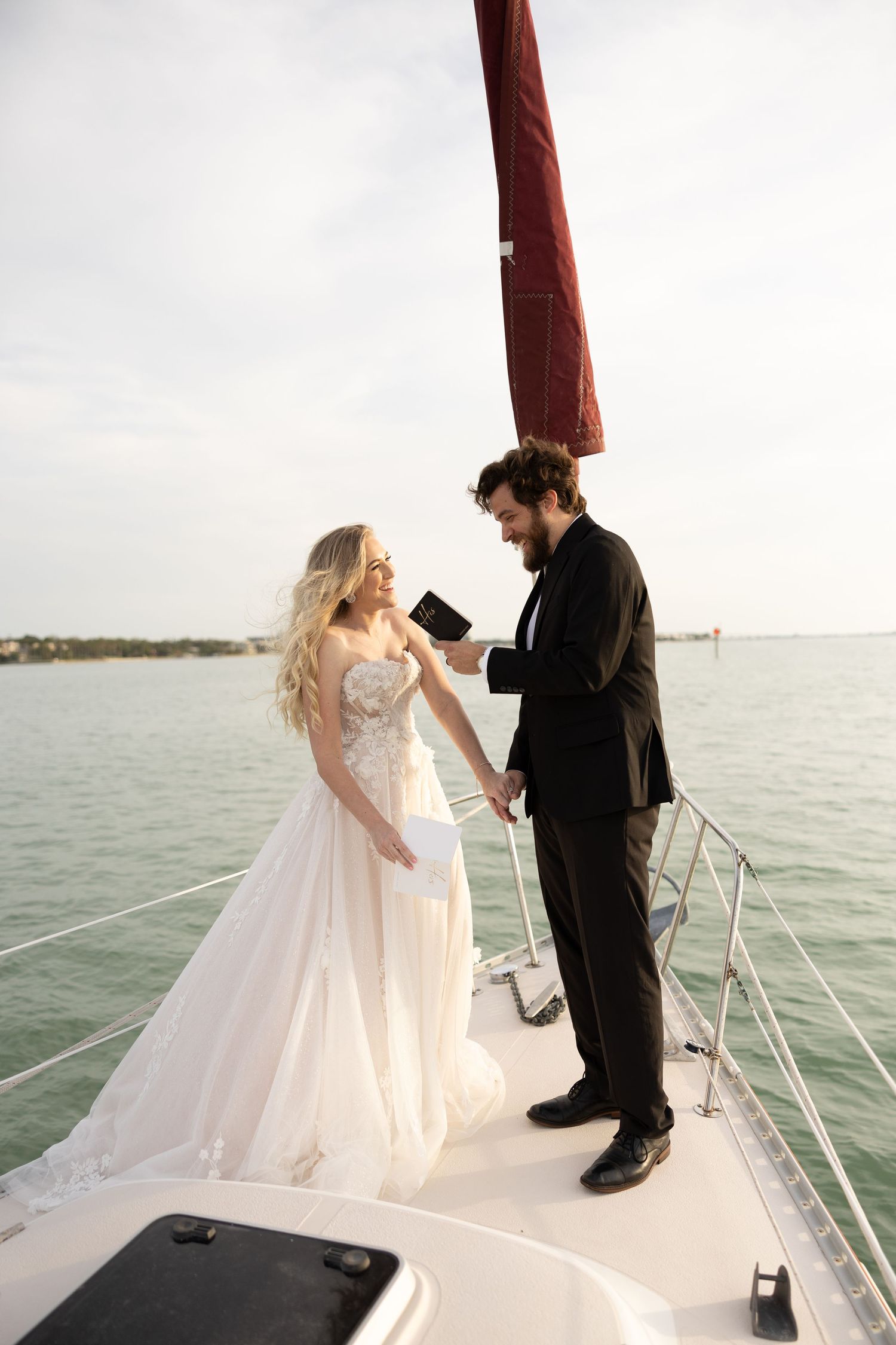 A couple reads vows during their intimate beach wedding ceremony surrounded by rocky coastal landscape.