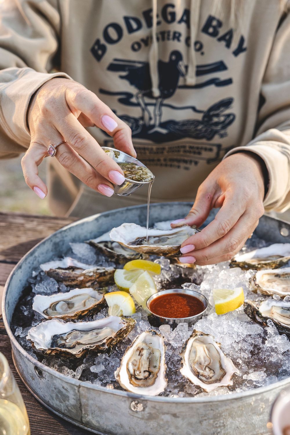 Fresh oysters on ice being garnished with lemon and cocktail sauce at a seafood restaurant.