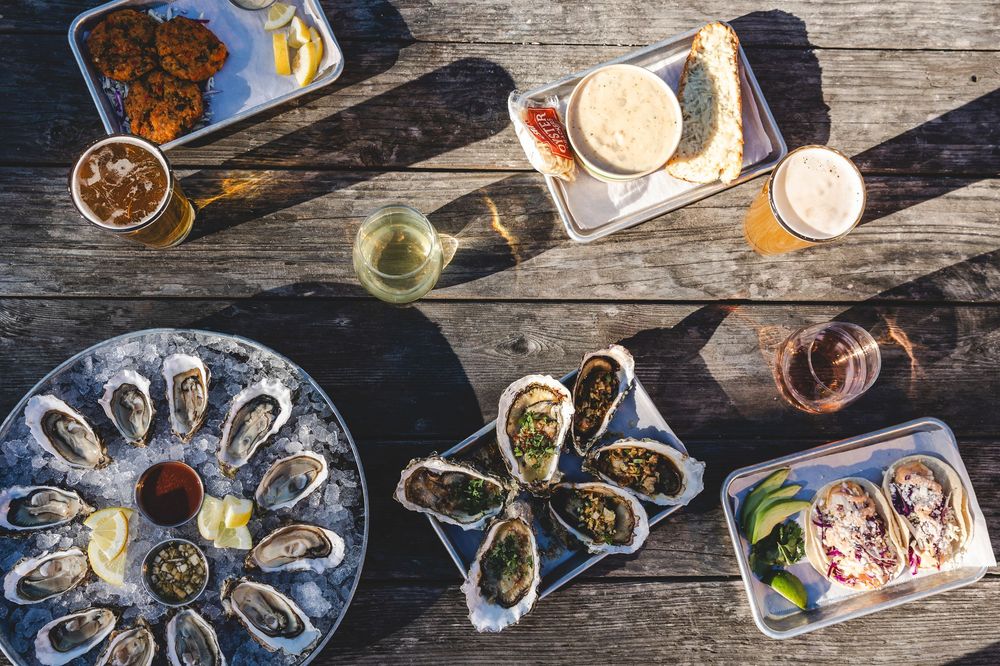 Fresh oysters and seafood platters arranged on rustic wooden table with various sauces and garnishes.