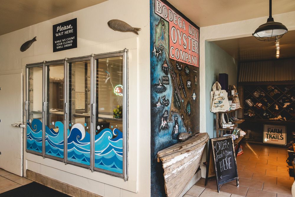 Interior view of a casual restaurant with blue wave murals painted on white walls and pendant lighting.