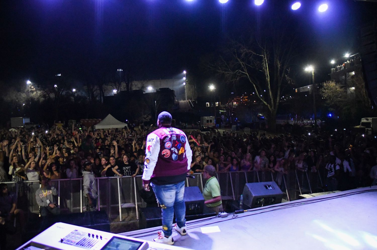 A concert performer on stage entertains a large crowd with dramatic lighting and stage effects during a nighttime show.