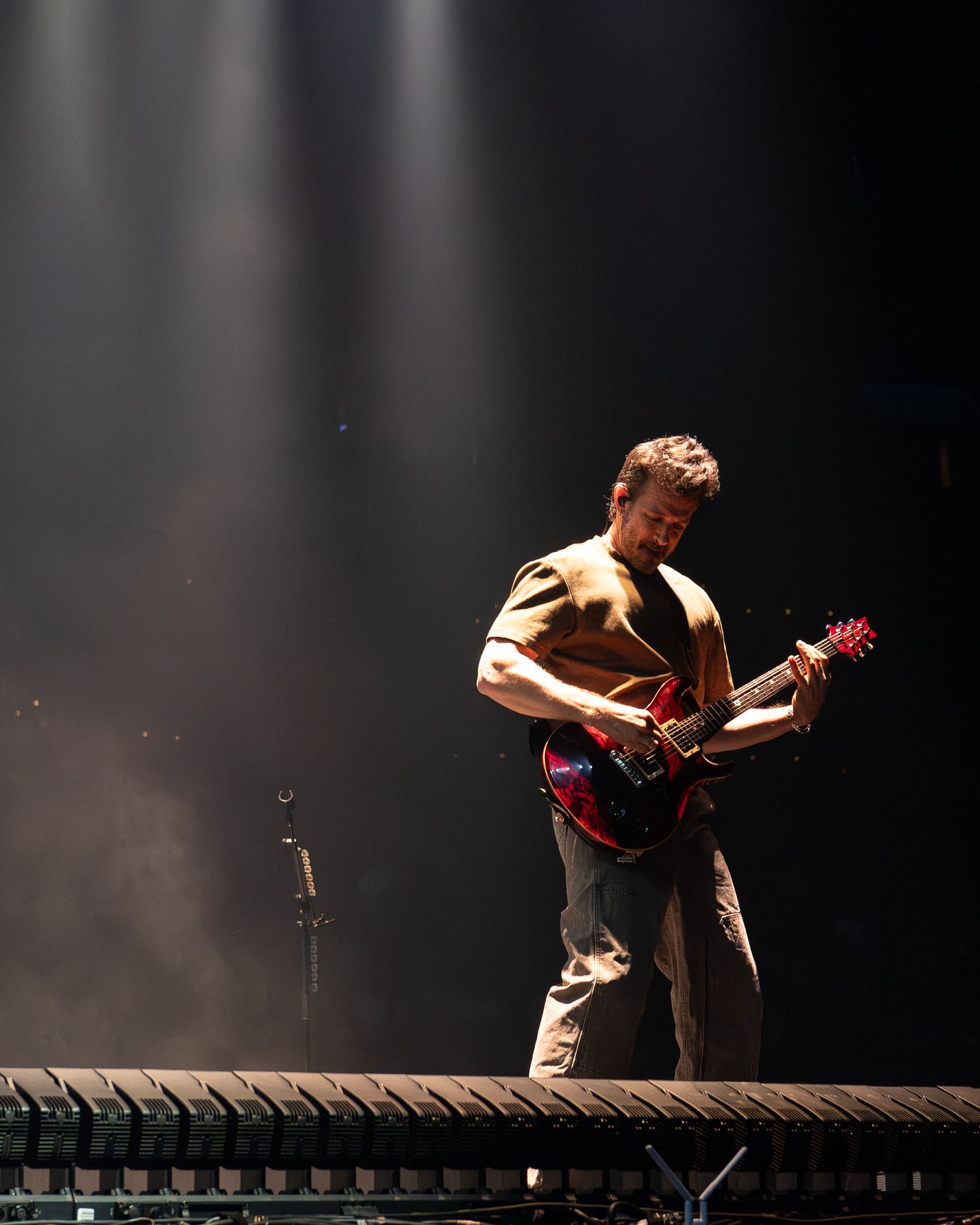Energetic performer bending backwards while playing guitar on an elevated platform during a concert performance.
