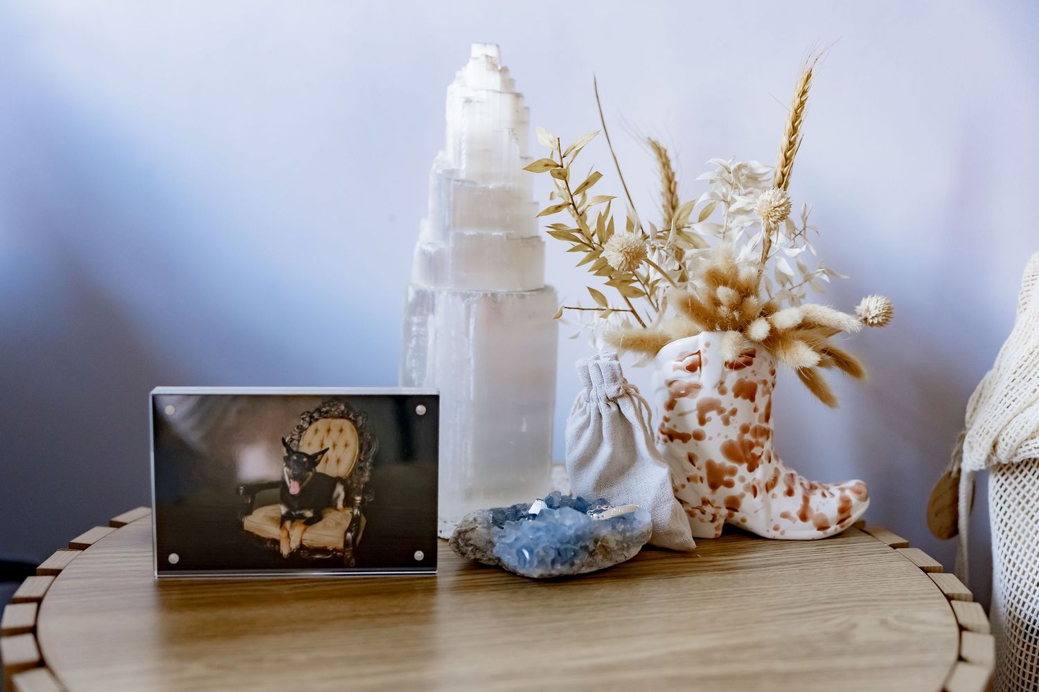 Decorative wooden table displaying a crystal geode, selenite tower, coral branch, and vintage framed photograph.
