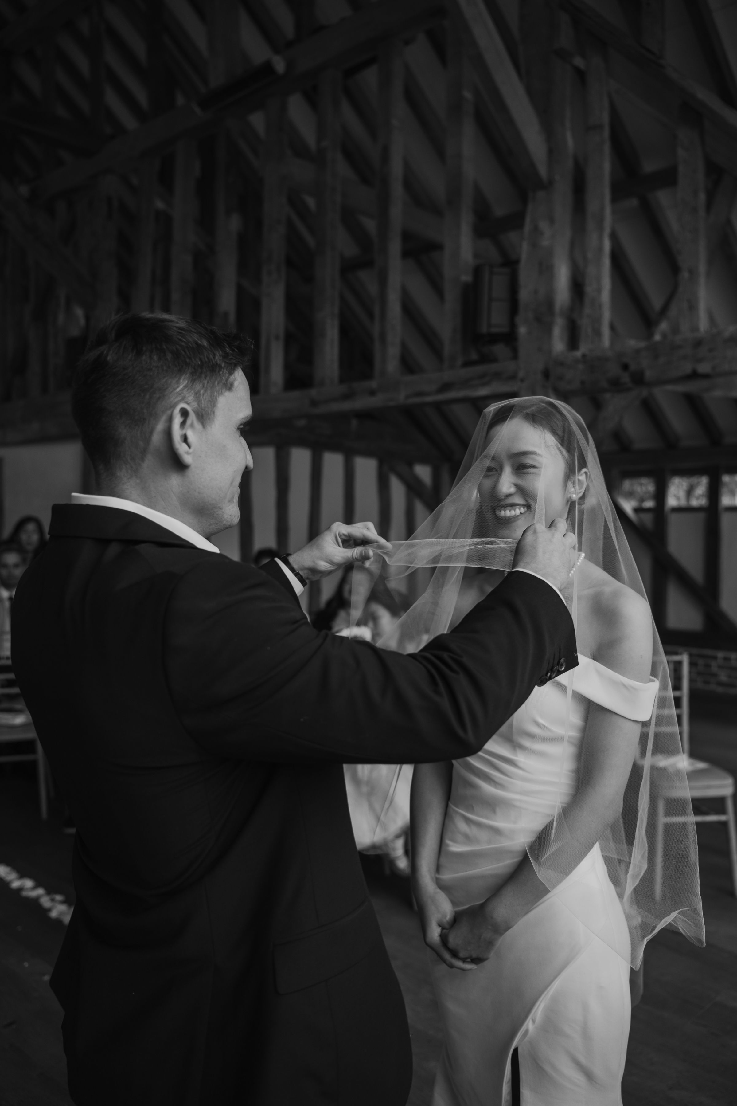 Couple dancing together in a rustic indoor venue with wooden beams visible in black and white sequence.