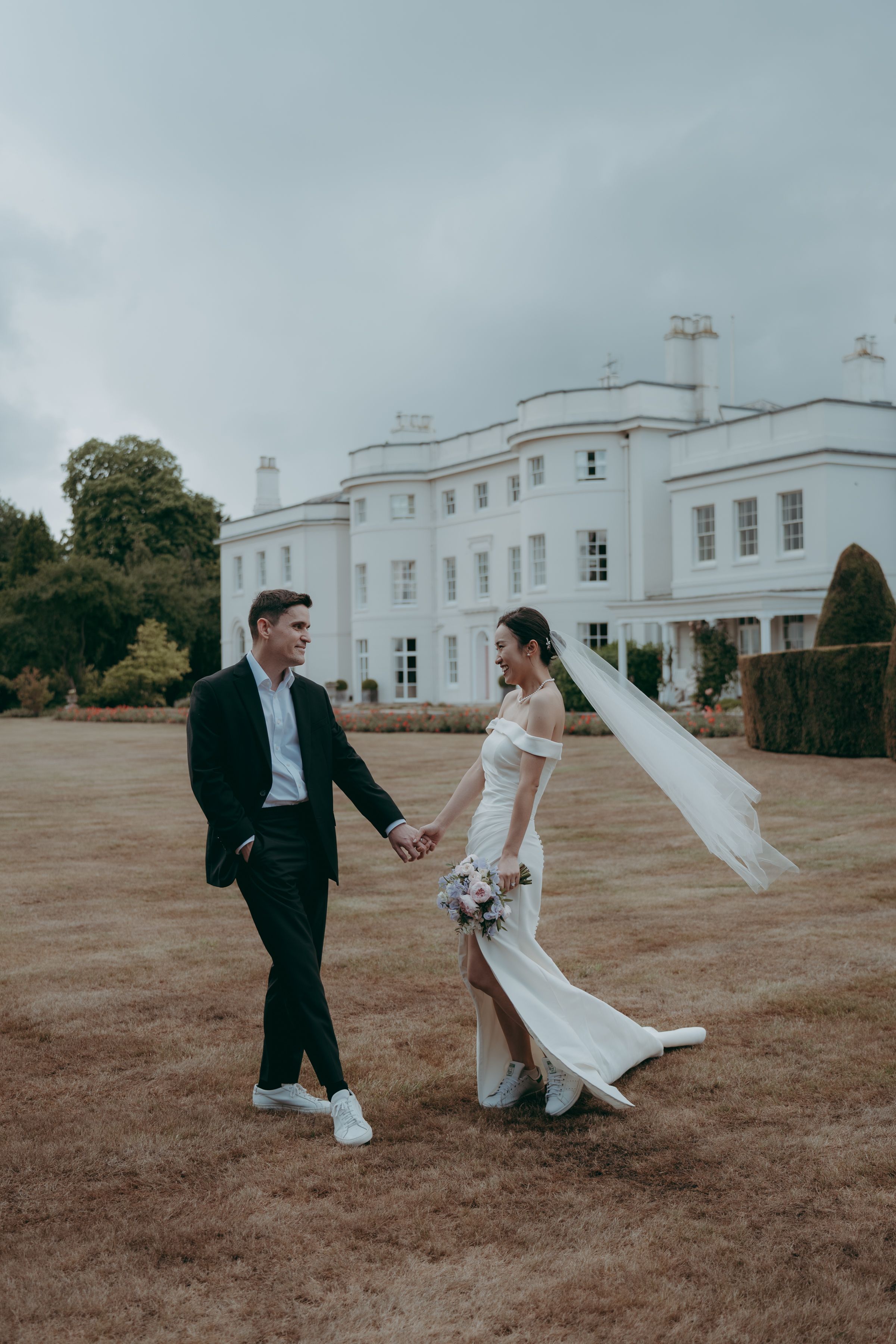 A series of playful wedding photos showing a couple dancing and twirling on a lawn in front of a white mansion.