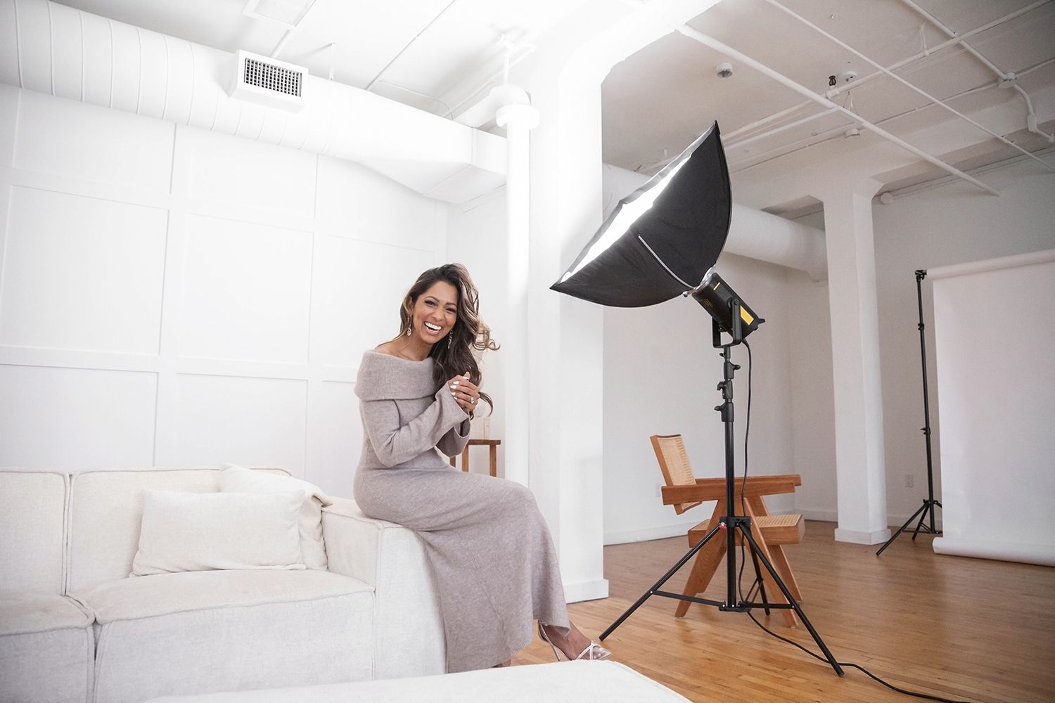 A cozy photo studio setup with white furniture and professional lighting equipment.