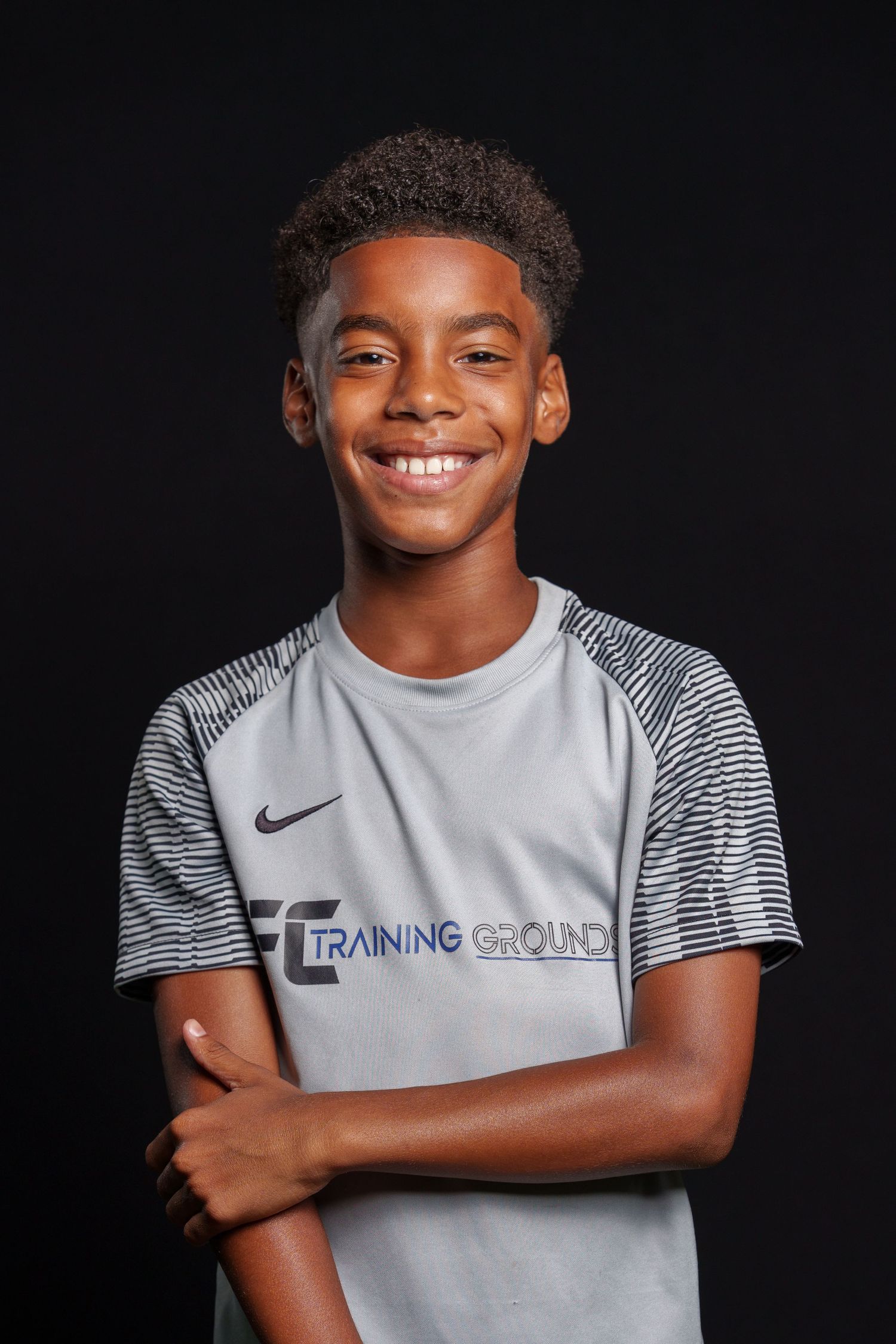 A sports player wearing a black Springfield uniform with orange accents and curly hair poses for a portrait.