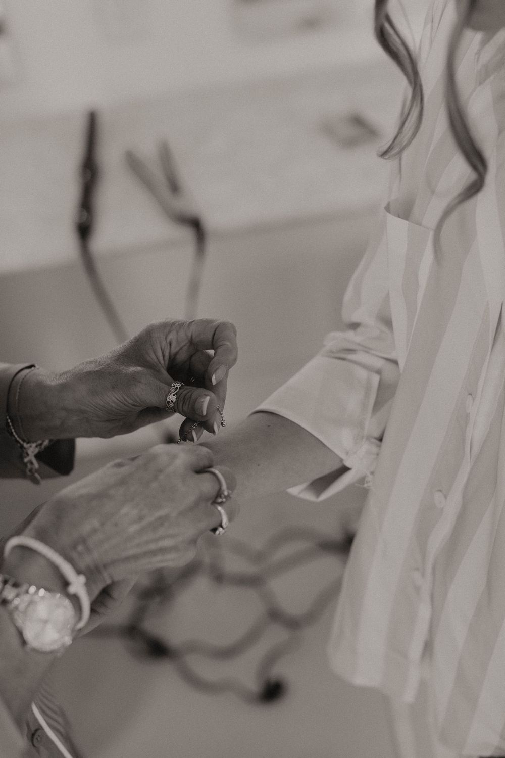 Close-up of hands adjusting details on white fabric during wedding preparations.