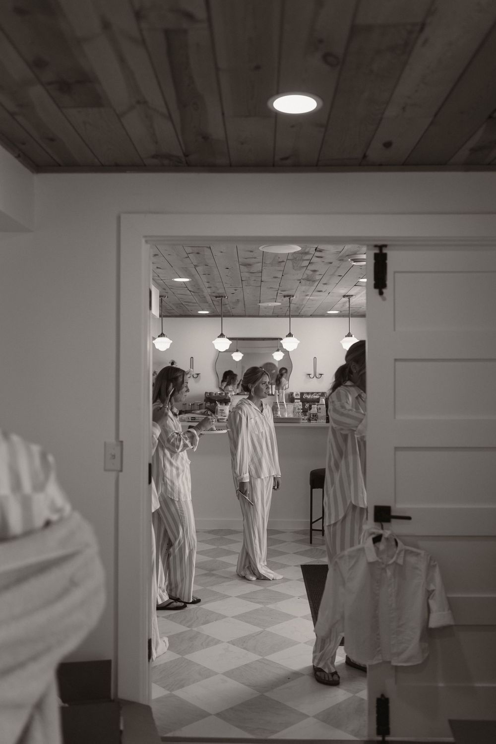 Wedding party members in matching robes gathered in a dressing room with checkerboard floors.