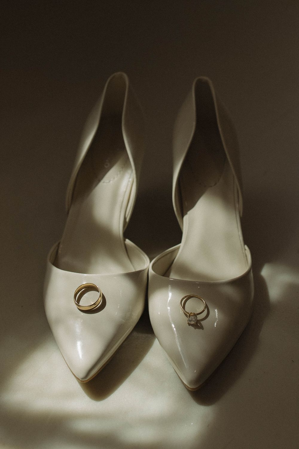 White bridal shoes with wedding rings placed on them in artistic composition.