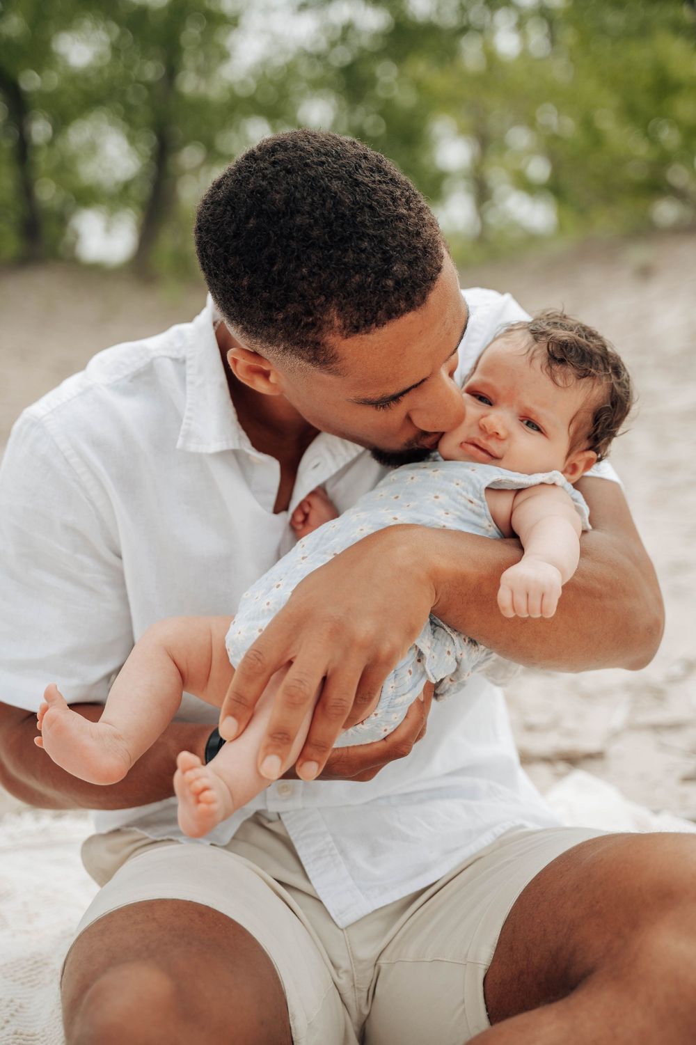 A tender moment between parent and baby as they share an intimate cuddle outdoors on a sunny day.