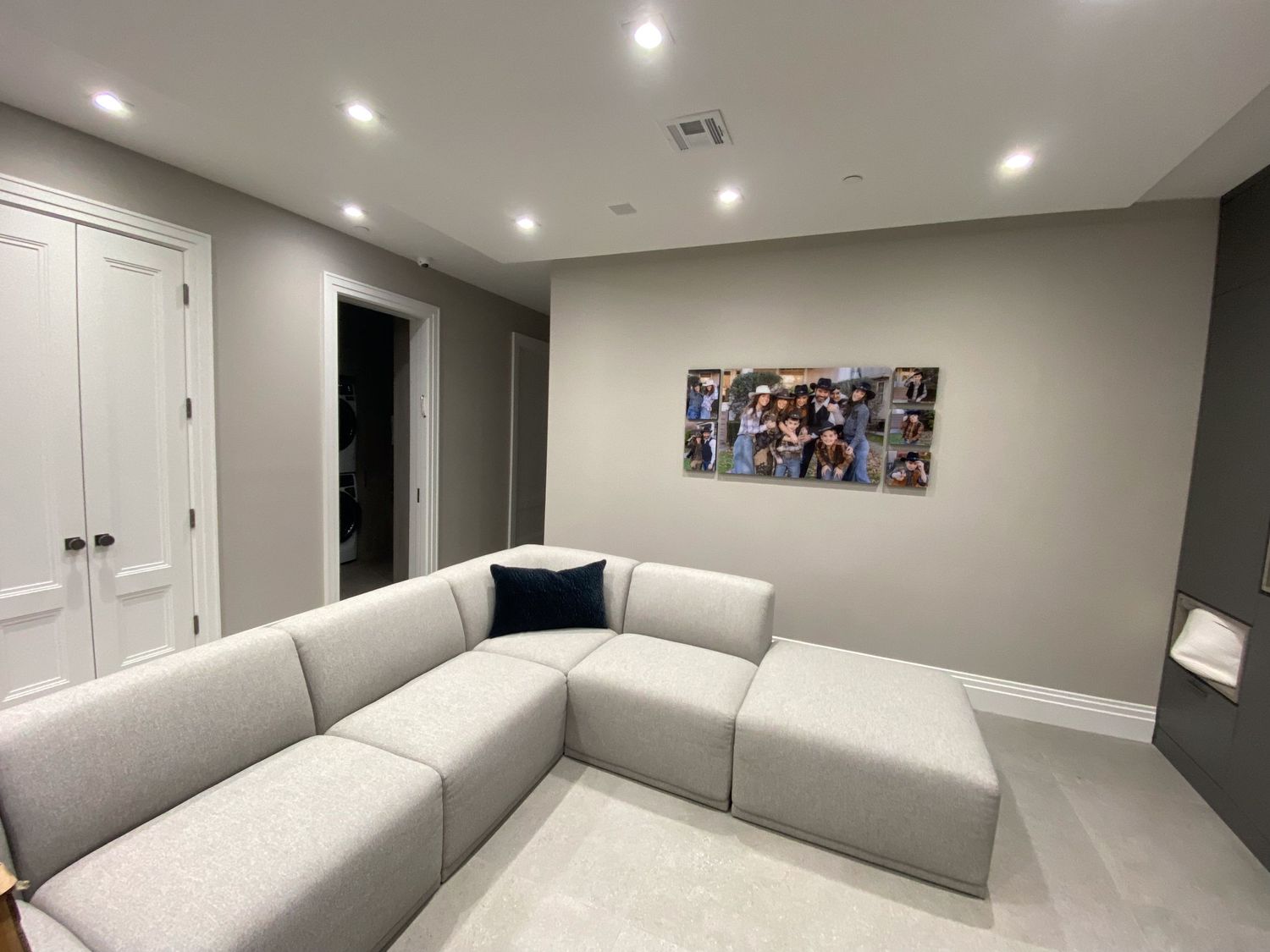 Large modern room with light gray walls, recessed lighting, and comfortable white sectional sofa.