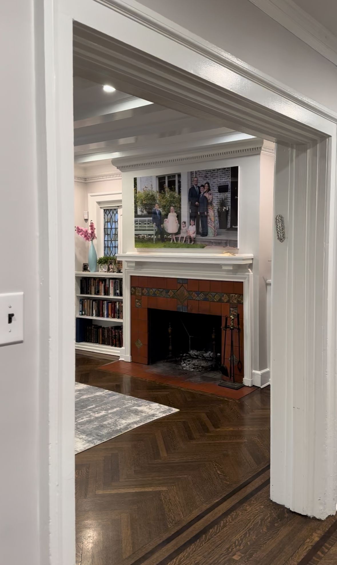 Modern interior space with herringbone wood floors and white columns and trim.