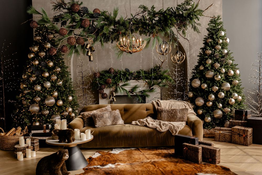 Christmas living room decor with plush couch, decorated trees, wrapped gifts, and elegant greenery hanging overhead.