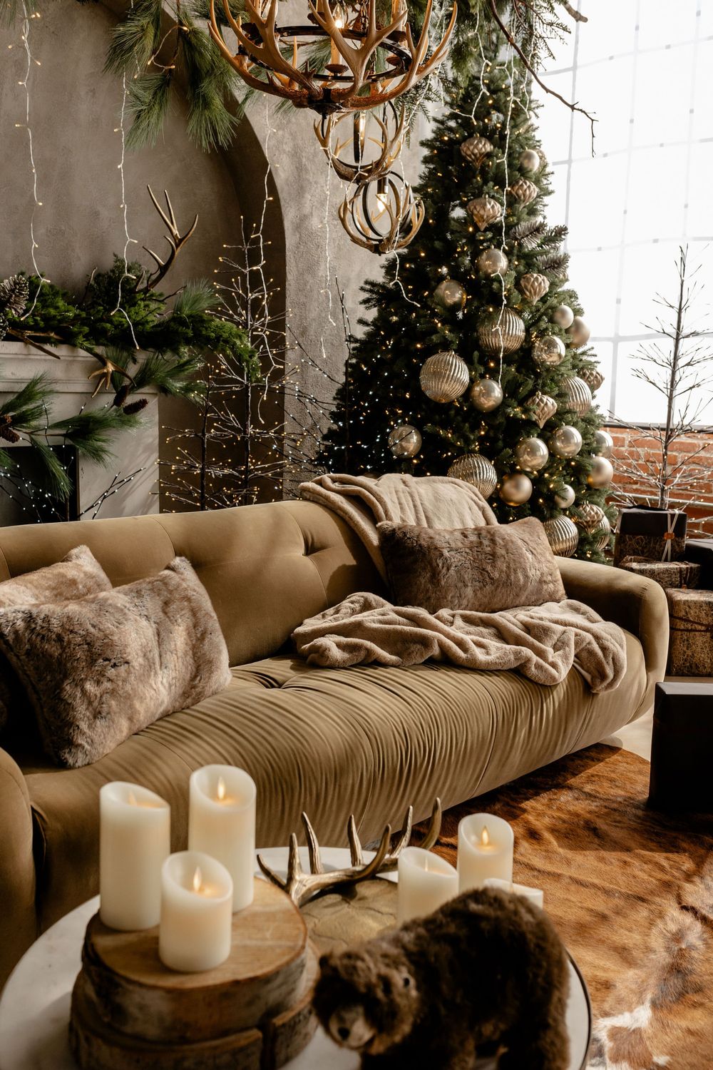 Cozy winter living room with beige couch, white candles, and festive holiday greenery decorations creating a warm atmosphere.