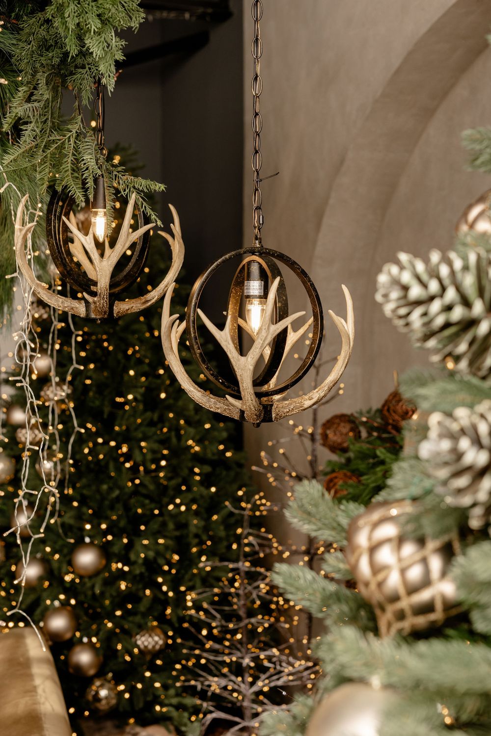 Elegant spherical pendant lights hang against a blurred Christmas tree backdrop with twinkling lights and ornaments.