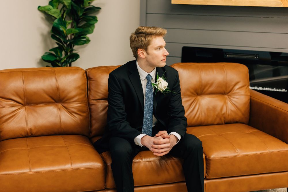 Side profile portrait on leather couch in formal attire.