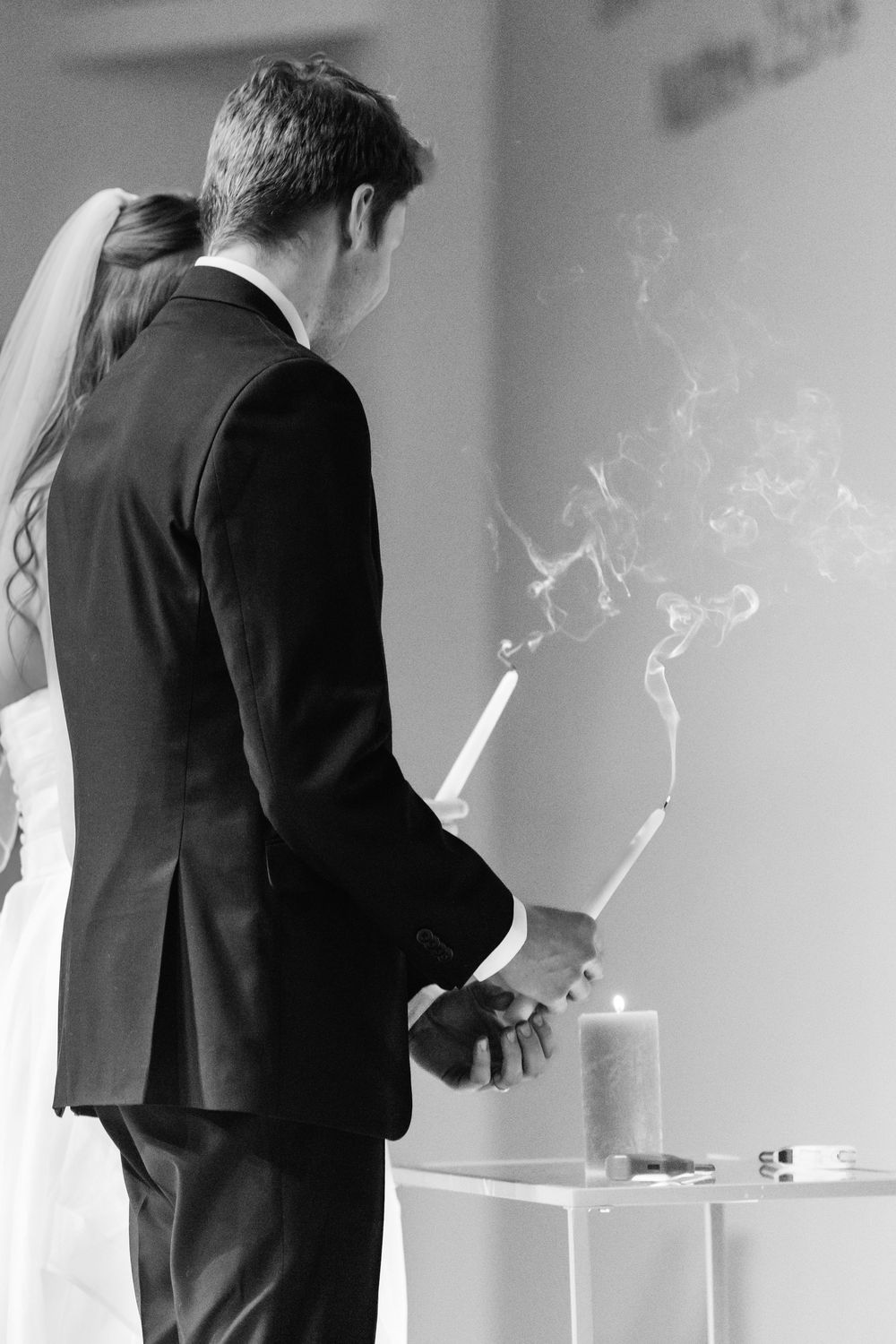 Black and white photo of a couple lighting unity candles during wedding ceremony.