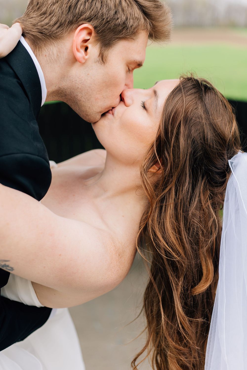Romantic wedding day kiss between couple in outdoor setting.