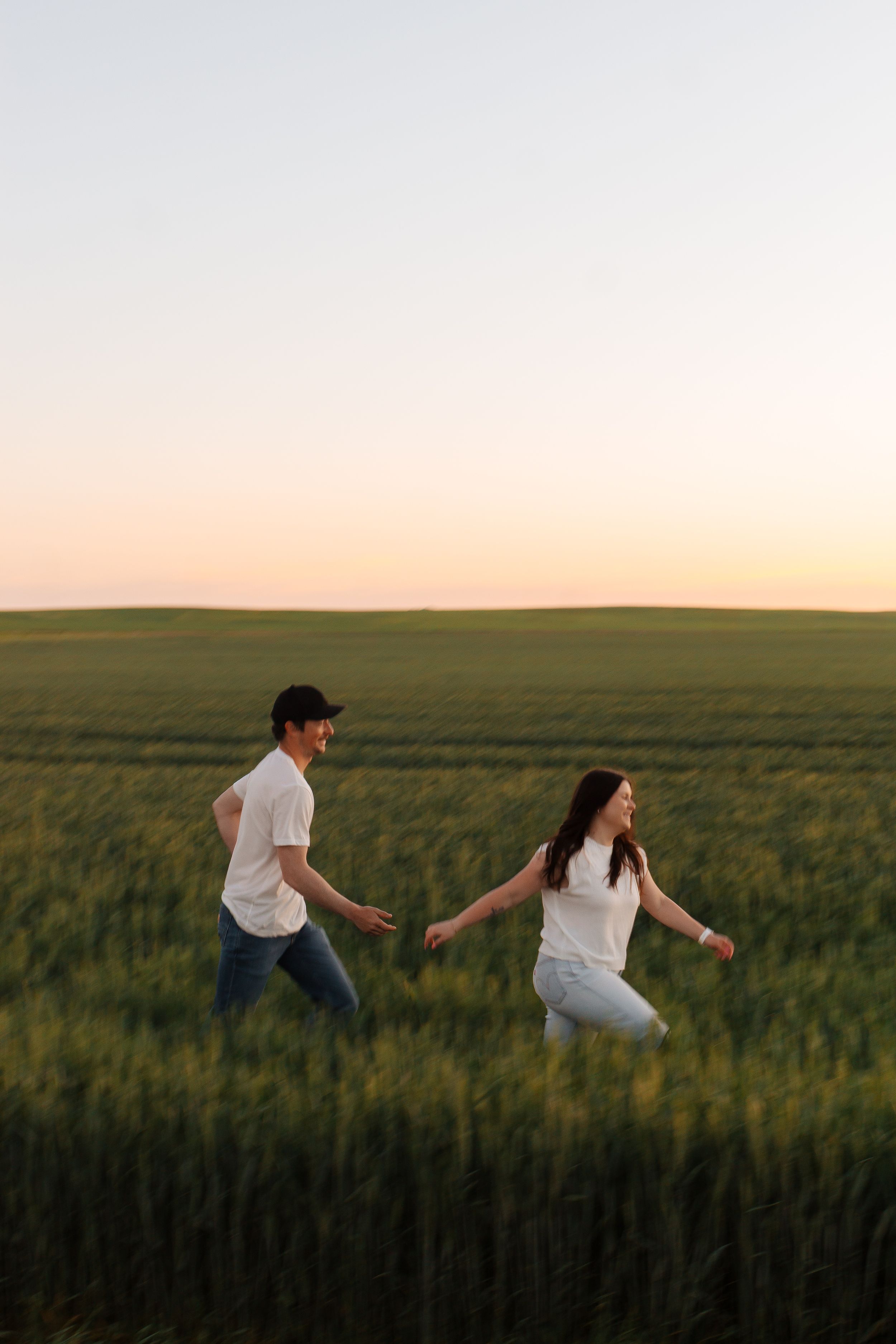 Couple running through Montana wheat field