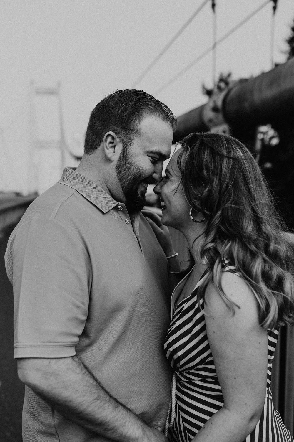 A romantic black and white portrait of a couple sharing a tender moment with the Golden Gate Bridge in background.