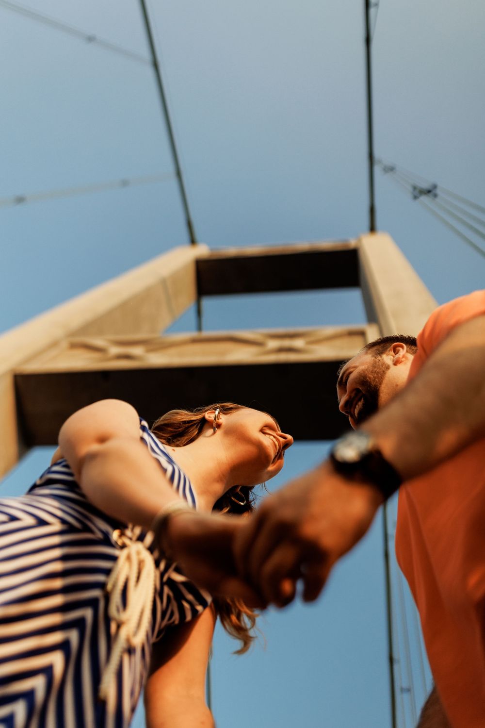 Low angle view of two people in sunglasses looking up at blue sky on summer day, one wearing striped clothing.